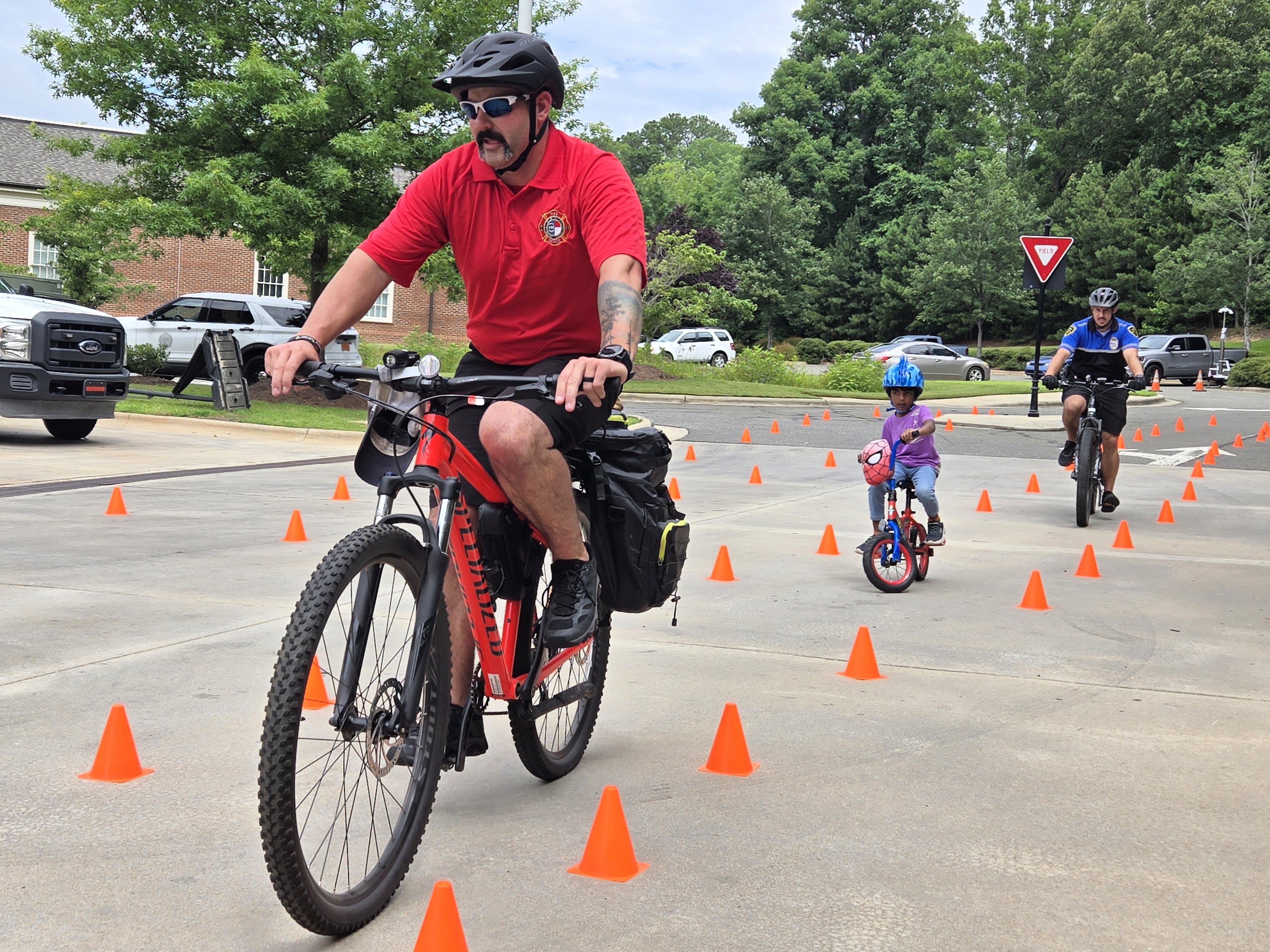 A photo of a firefighter and police officer riding bicycles with a child
